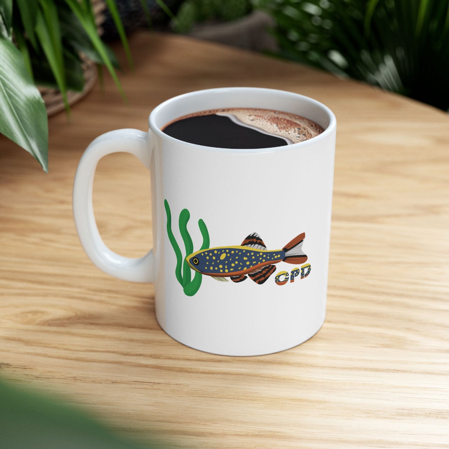 White ceramic Celestial Pearl Danio mug with fish and aquatic plant design filled with coffee