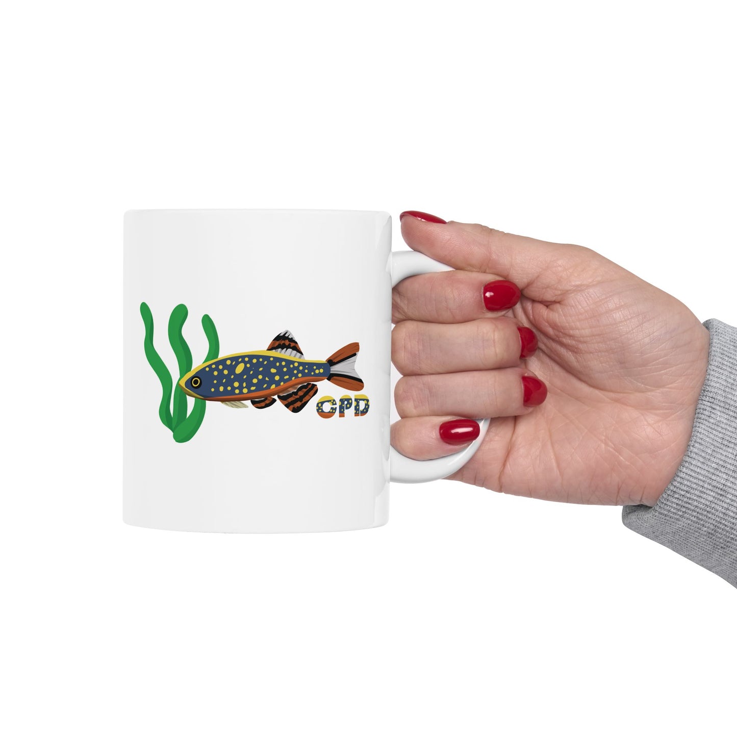 Hand holding Celestial Pearl Danio mug with fish and seaweed design on white background