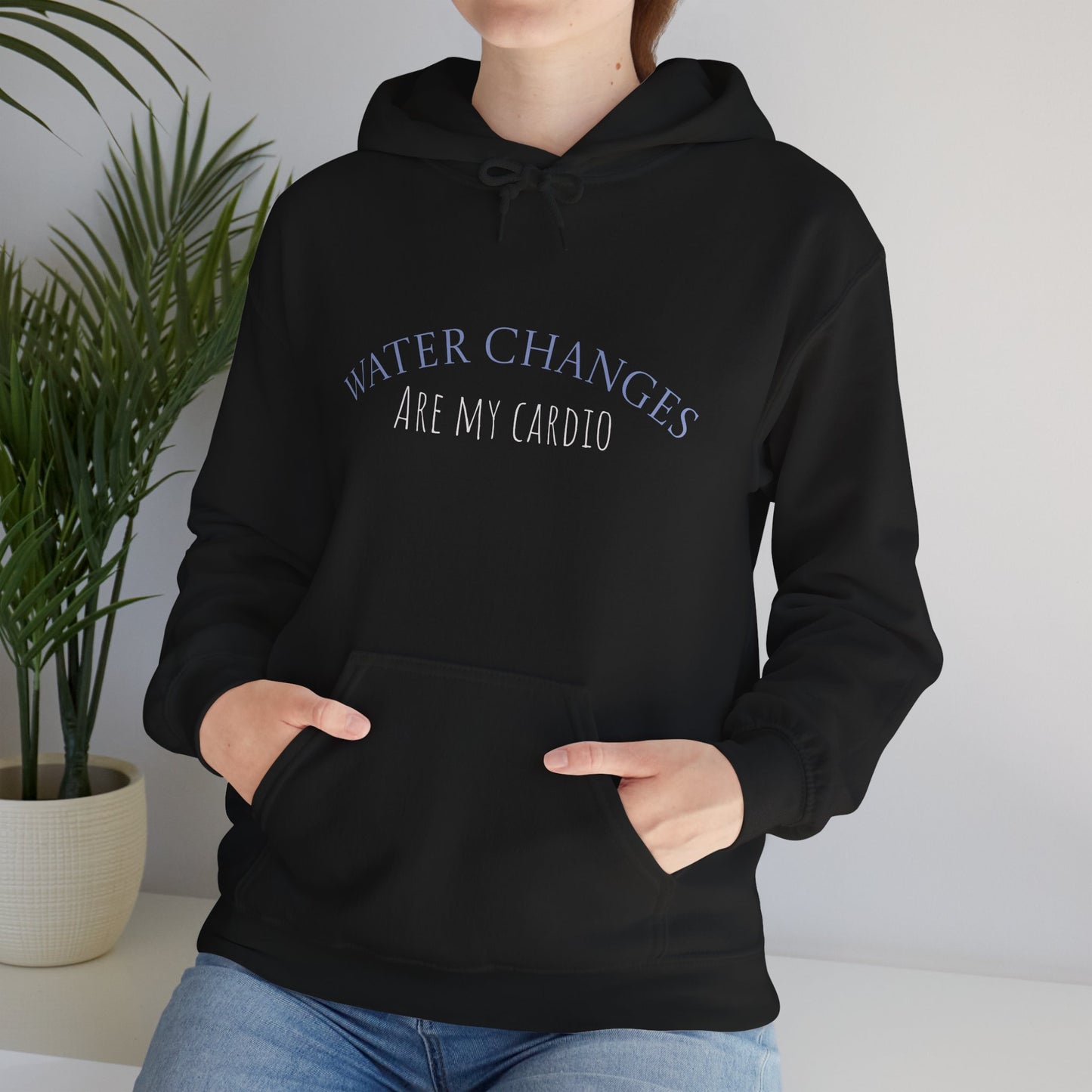 Black funny fishkeeping hoodie with Water Changes Are My Cardio text worn by person sitting indoors