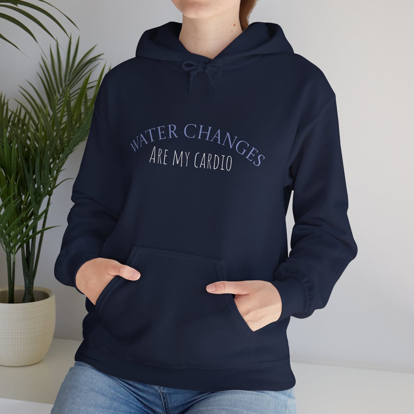 Woman wearing navy “Water Changes Are My Cardio” hoodie with hands in front pocket