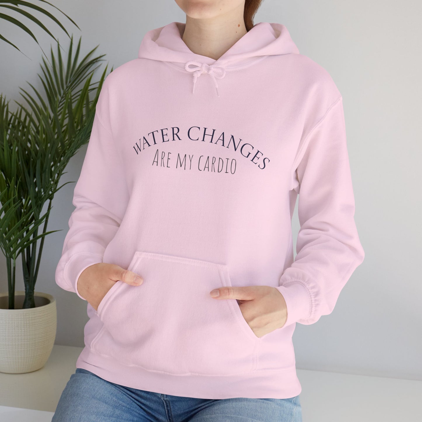 Woman wearing pink “Water Changes Are My Cardio” hoodie with hands in front pocket