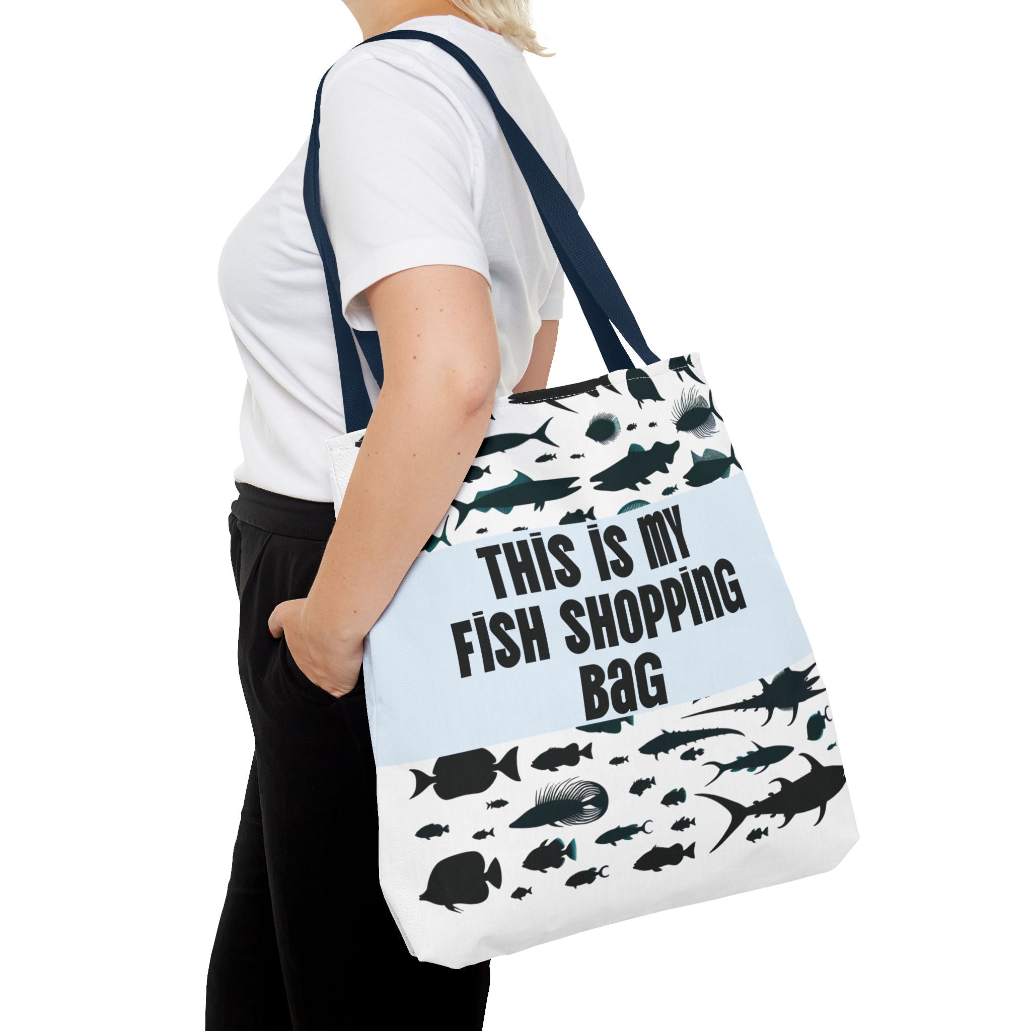 Person holding a tote bag with fish designs and text on a white background