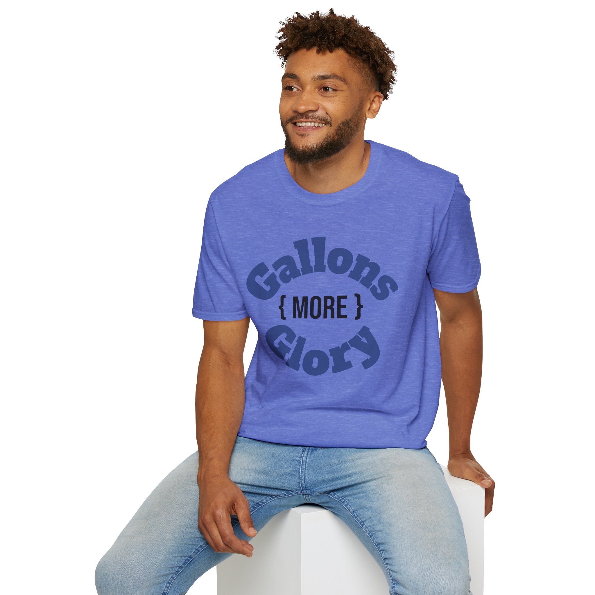 Smiling man wearing blue “More Gallons More Glory” shirt while sitting on a stool