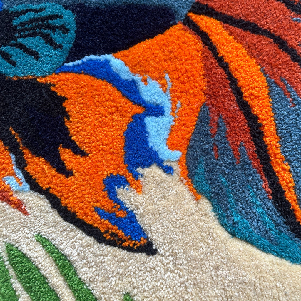 Colorful close-up of handmade betta fish rug showing vibrant orange, blue, and green textured fibers