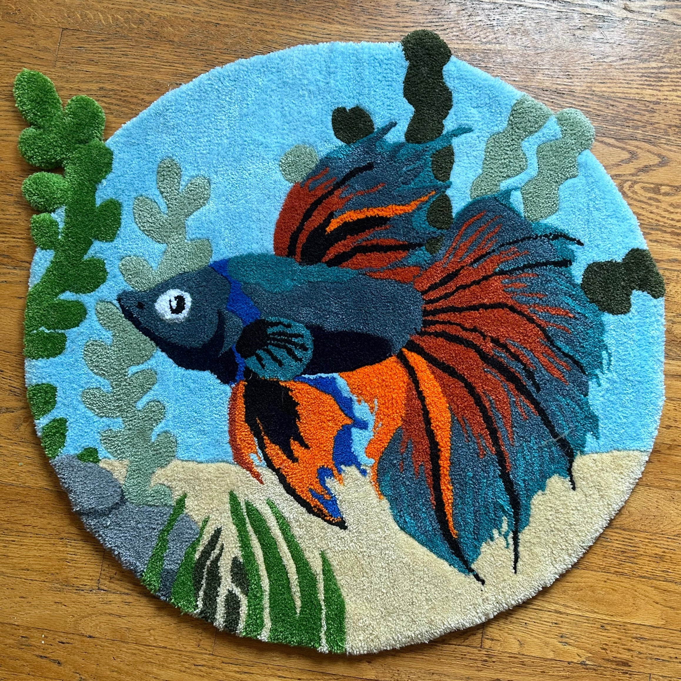 Handmade betta fish rug with vibrant orange and blue fish design surrounded by underwater plants
