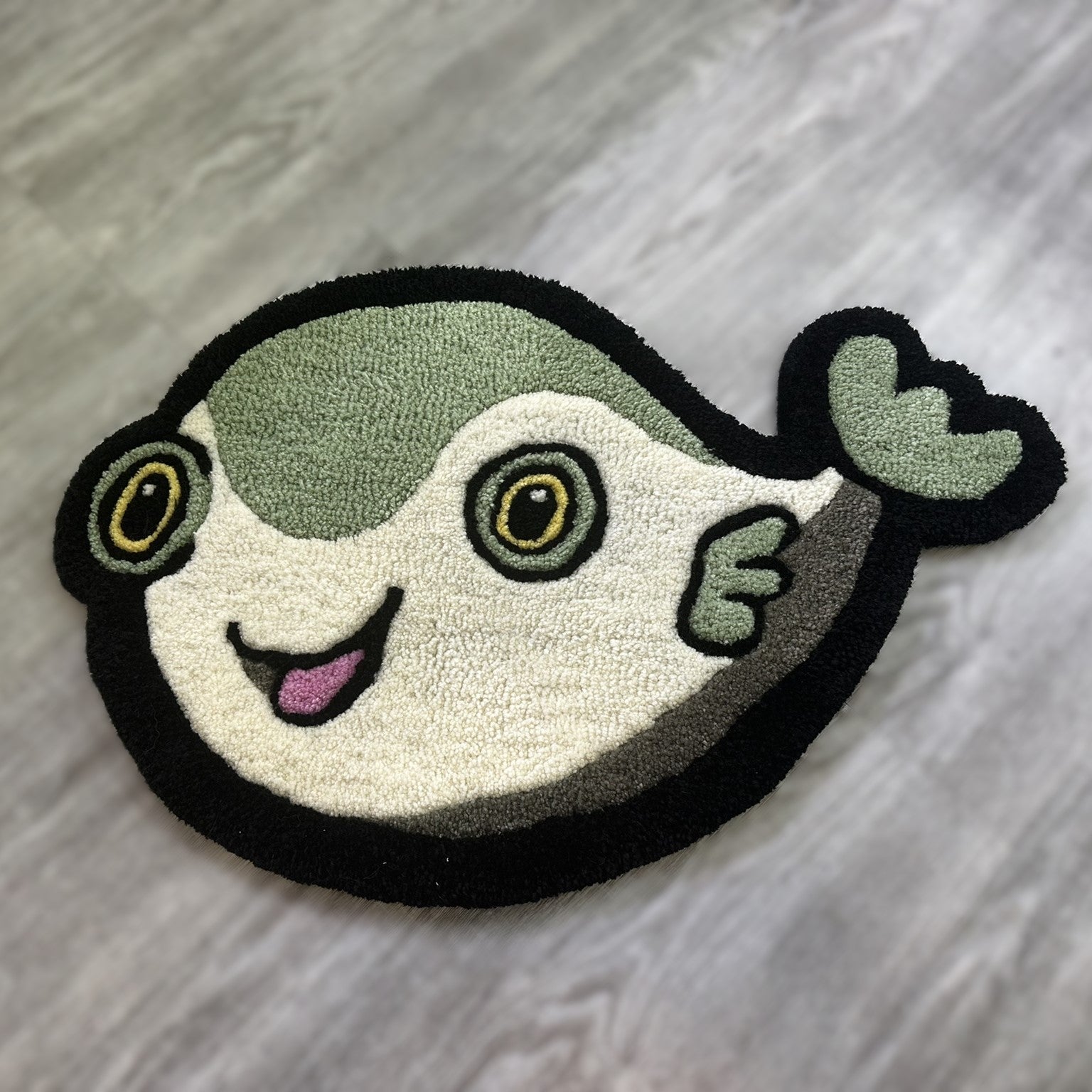 Cute Fish Rug by Scallywags Fish Bowl featuring a smiling green and white fish design on gray floor