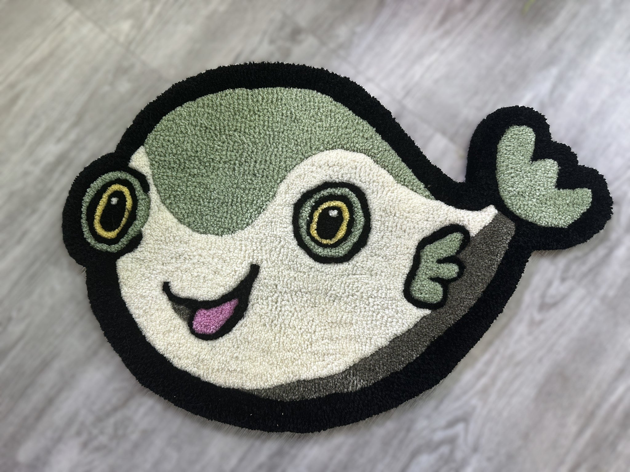 Scallywags Fish Bowl cute fish rug with green and white colors and black border on wood floor