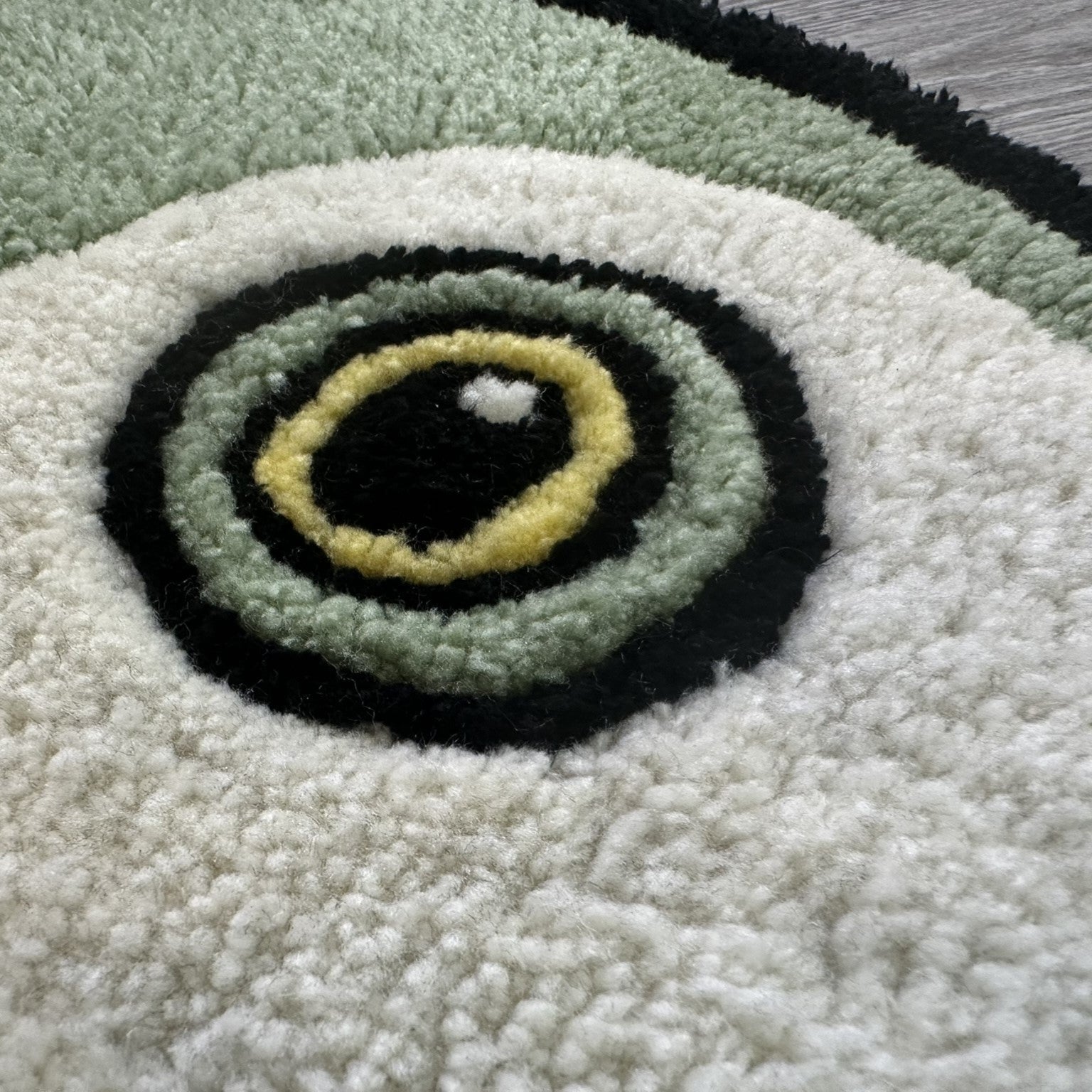 Close up of Scallywag's Fish Bowl Cute Fish Rug showing textured green white and black fish eye design