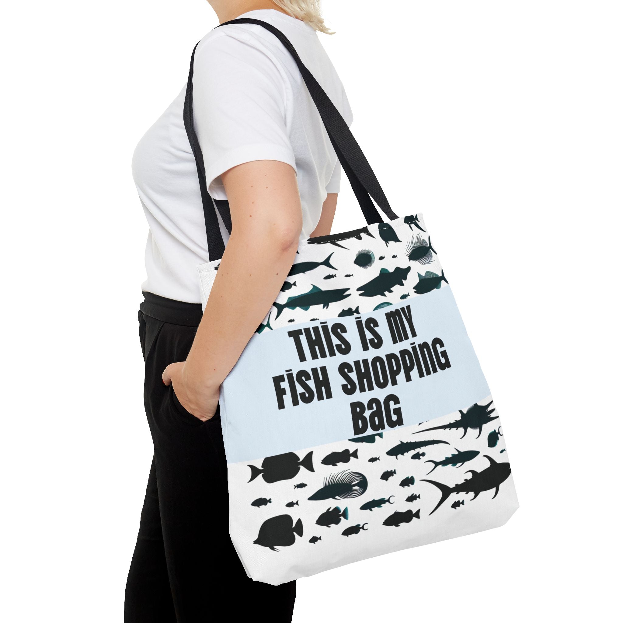 Person holding a tote bag with fish designs and text on a white background