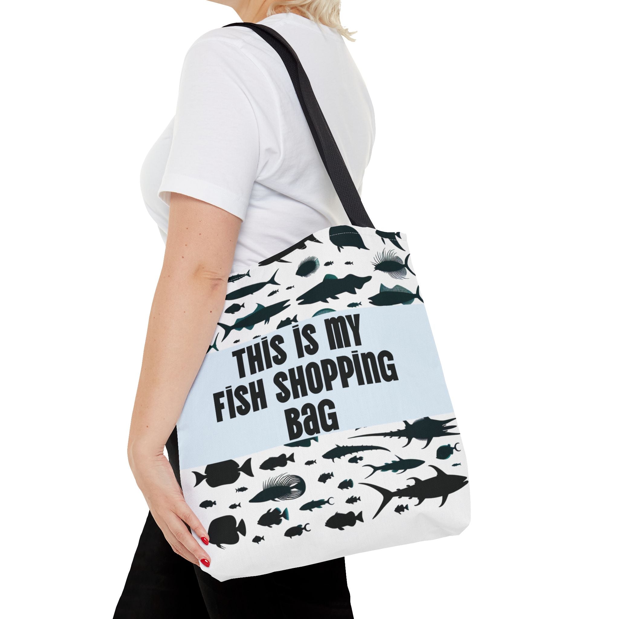 Person holding a tote bag with fish designs and text on a white background
