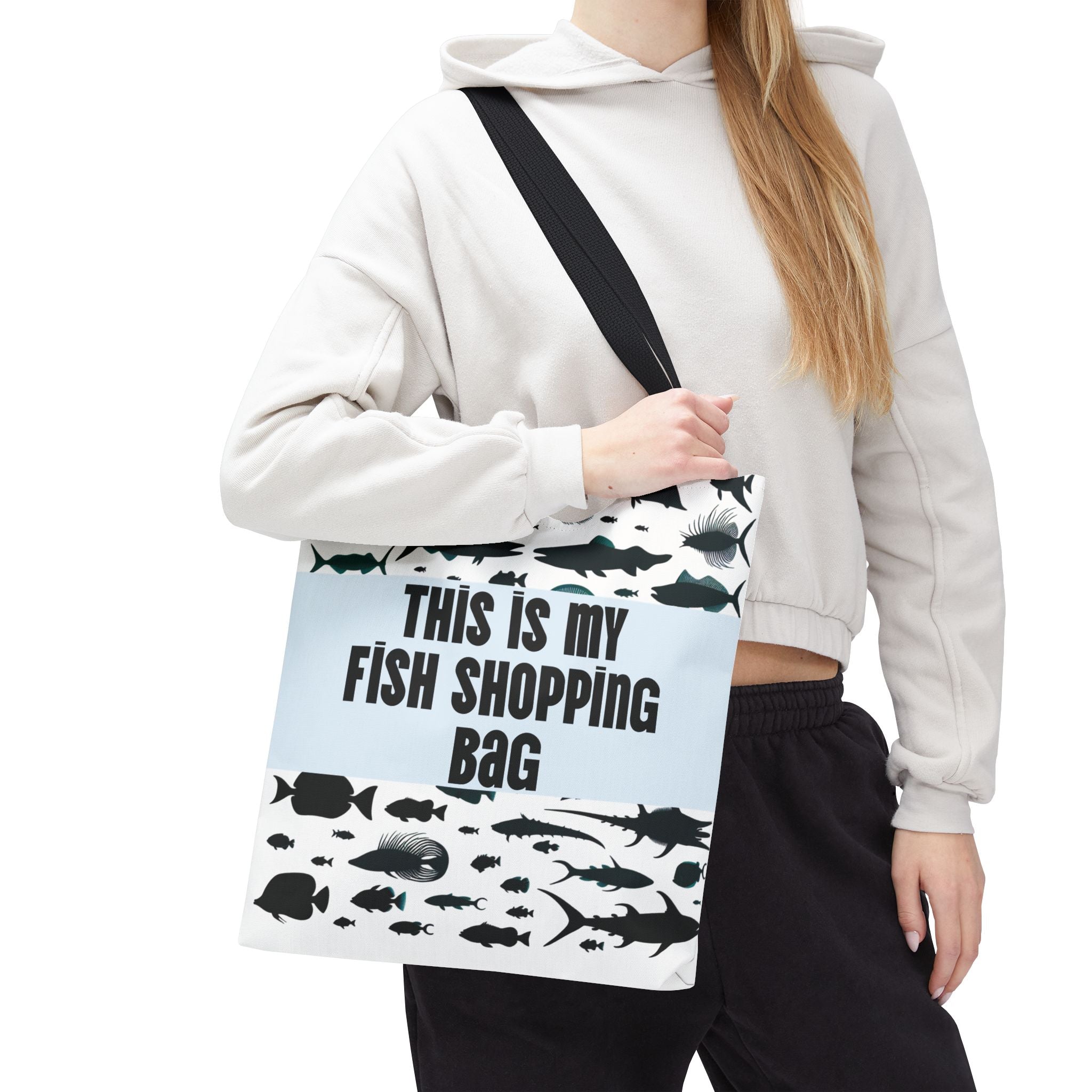 Person holding a tote bag with fish designs and text on a white background