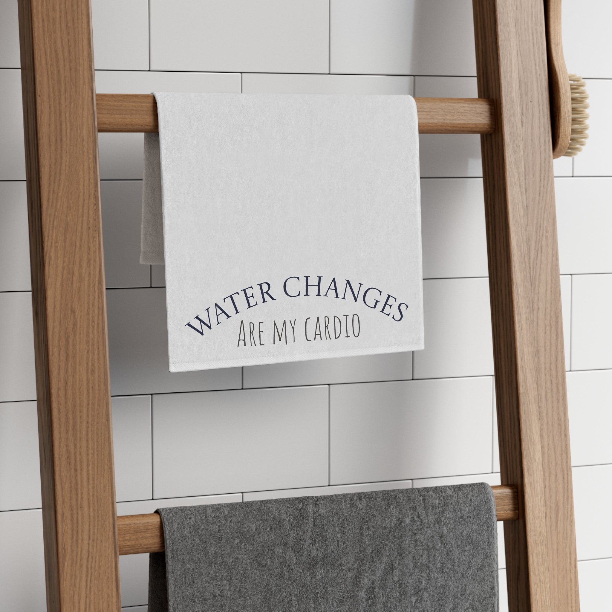 White fish tank cleaning cloth with Water Changes Are My Cardio text hanging on wooden towel rack