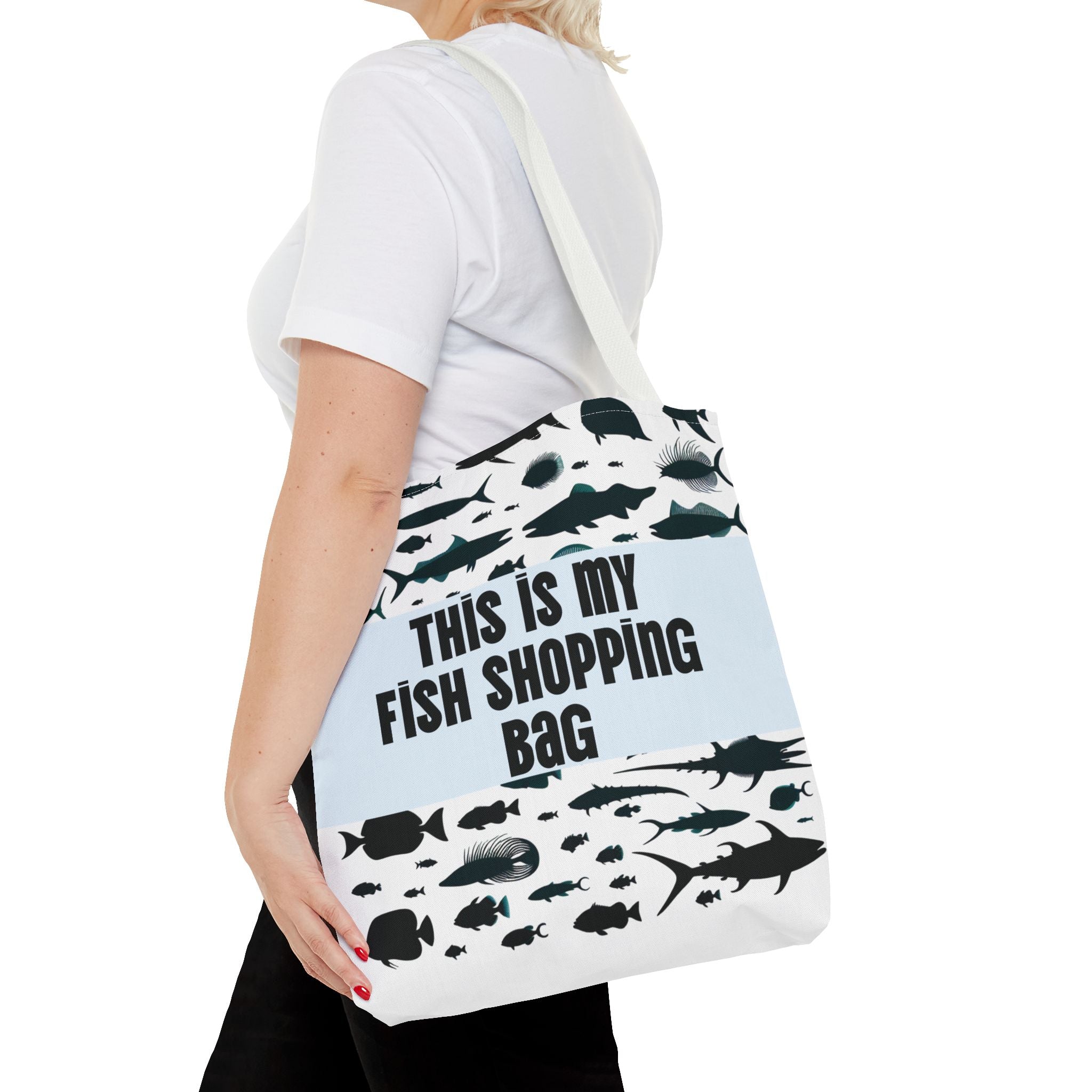 Person holding a tote bag with fish designs and text on a white background