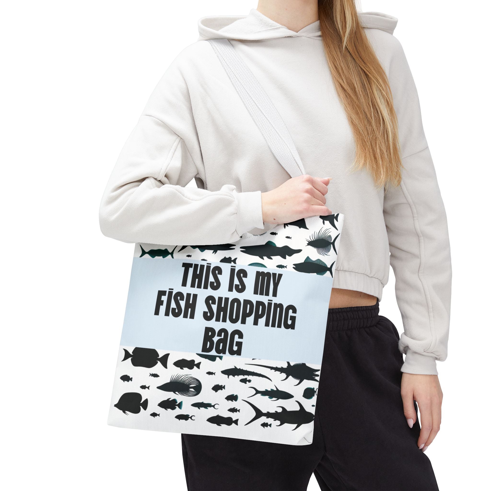 Person holding a tote bag with fish design and text 'This is my fish shopping bag' on a white background