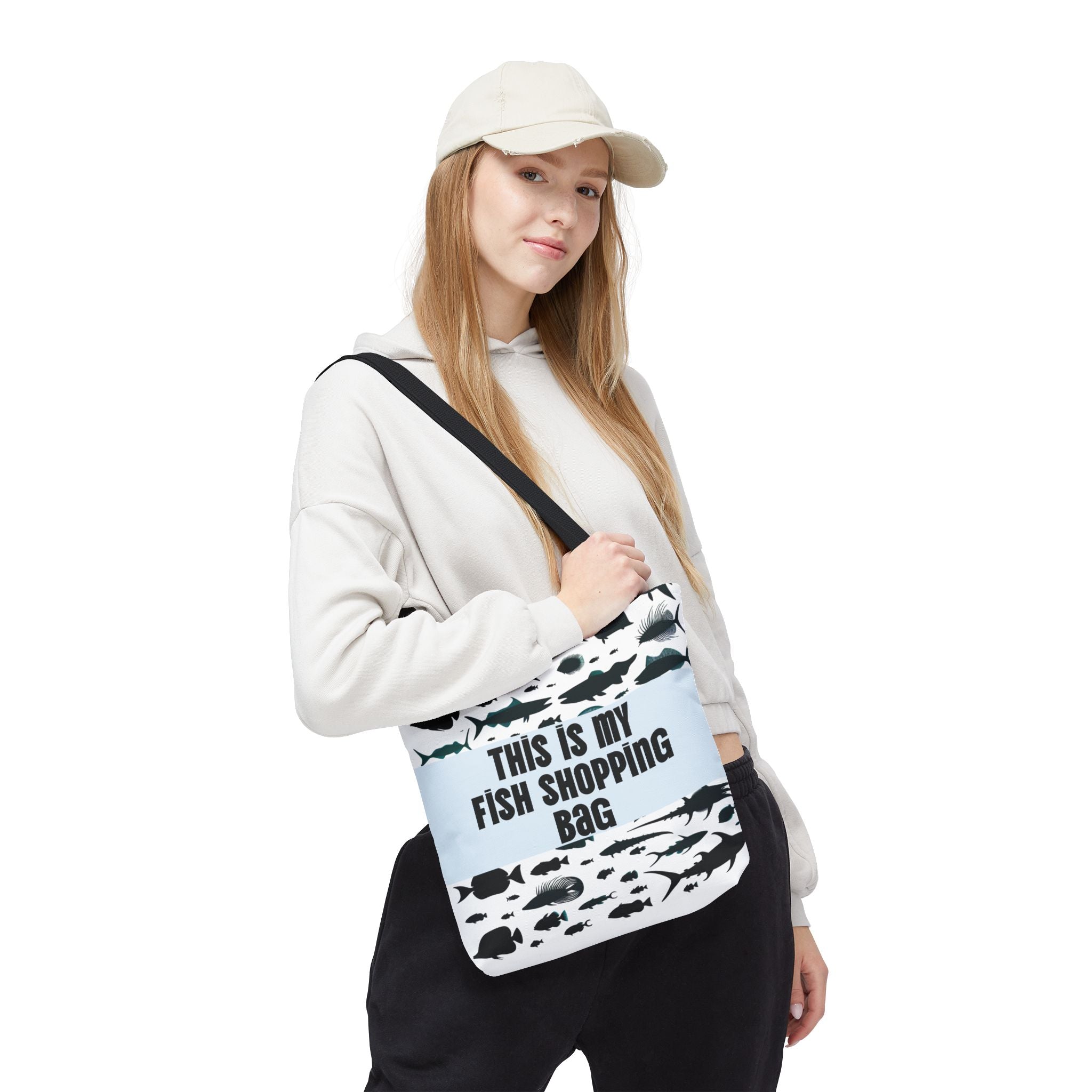 Woman wearing a funny fish-themed tote bag with black fish prints and text This is my fish shopping bag