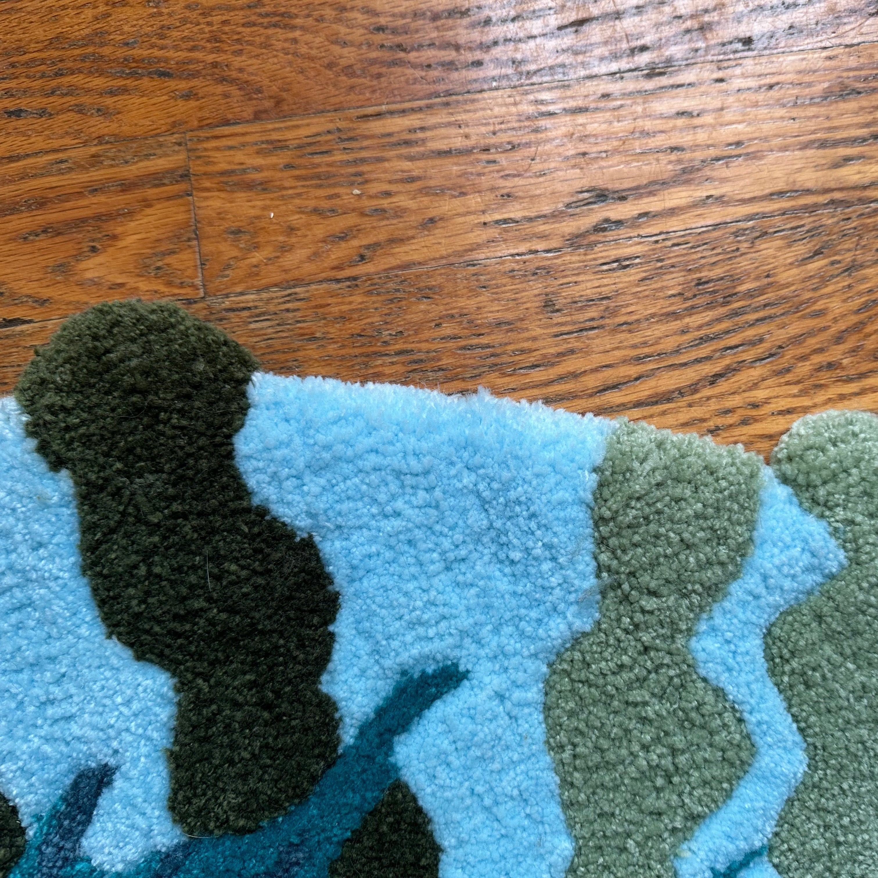 Close-up of handmade betta fish rug showing textured blue and green tufted wool fibers