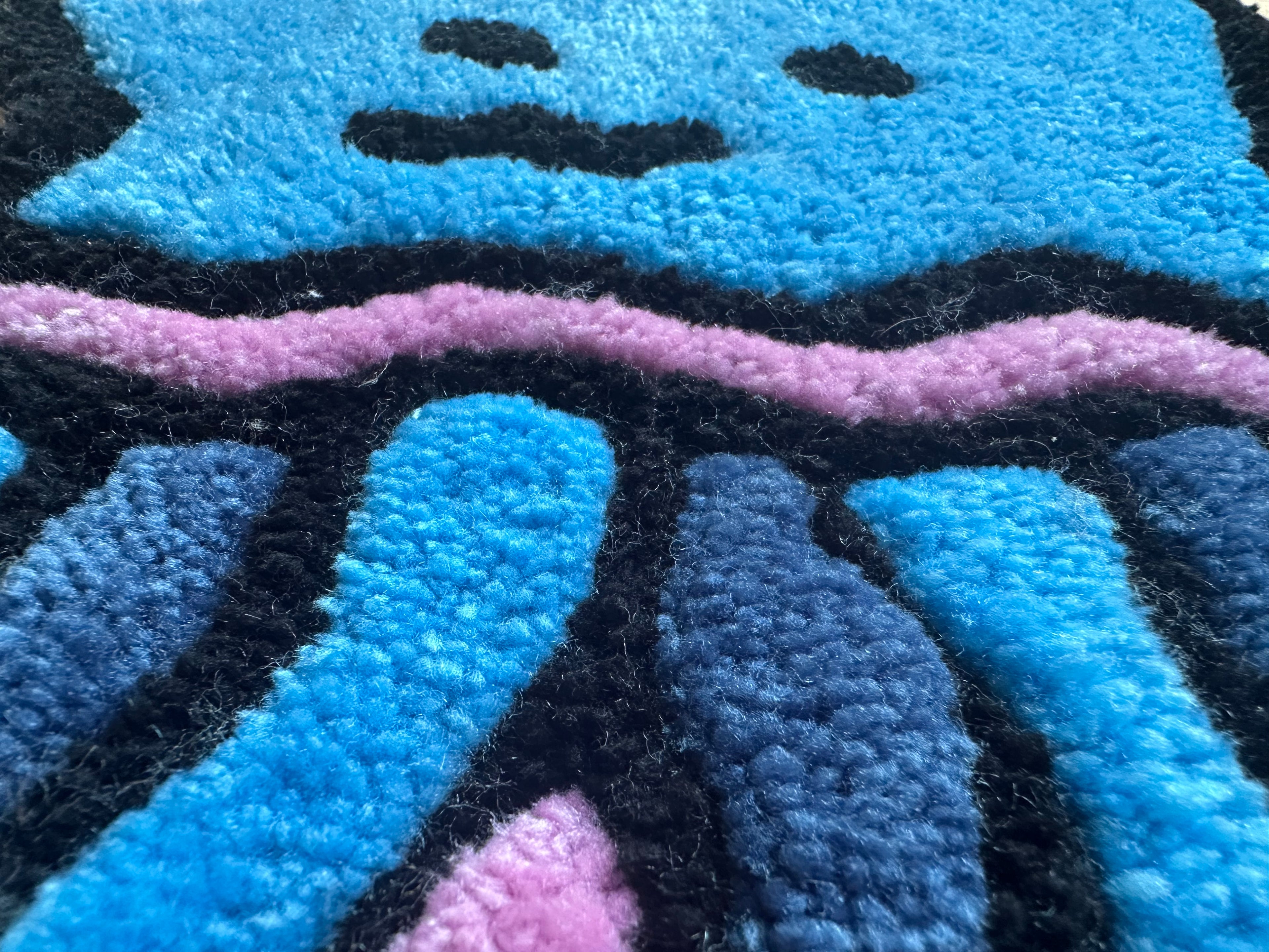 Close-up of Scallywag's Fish Bowl handmade jellyfish rug showing blue, pink, and black textured fibers