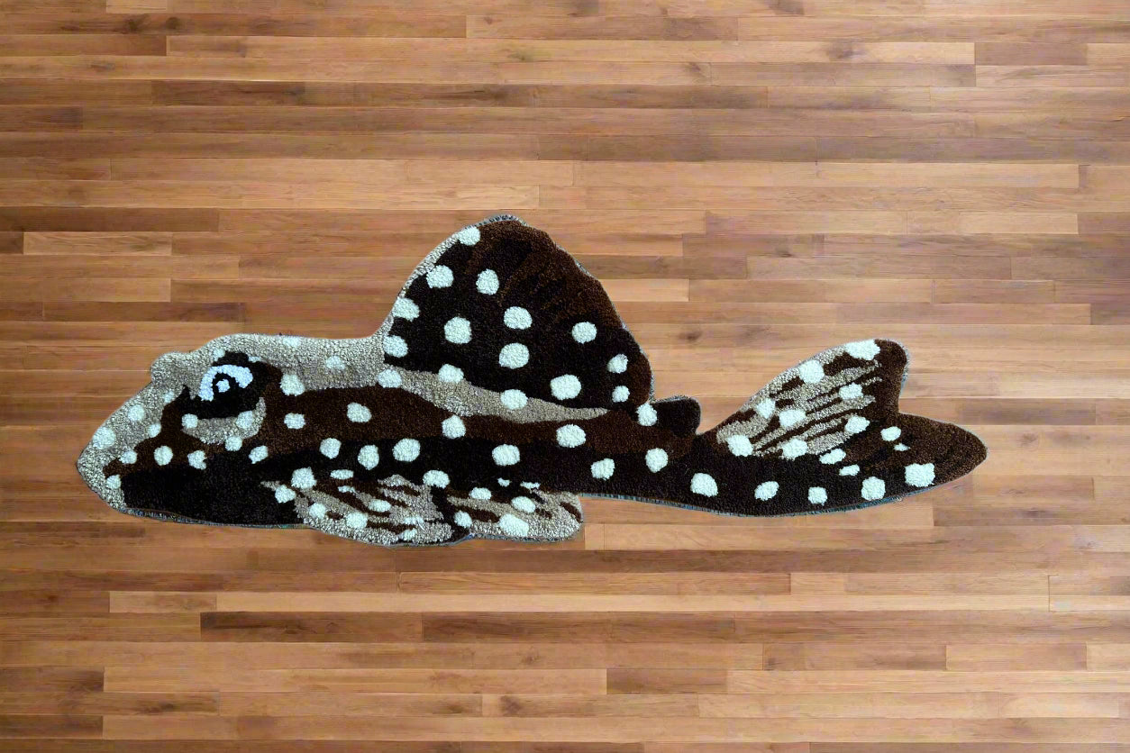 Handmade pleco rug by Scallywags Fish Bowl shaped like a spotted brown pleco fish on wooden floor