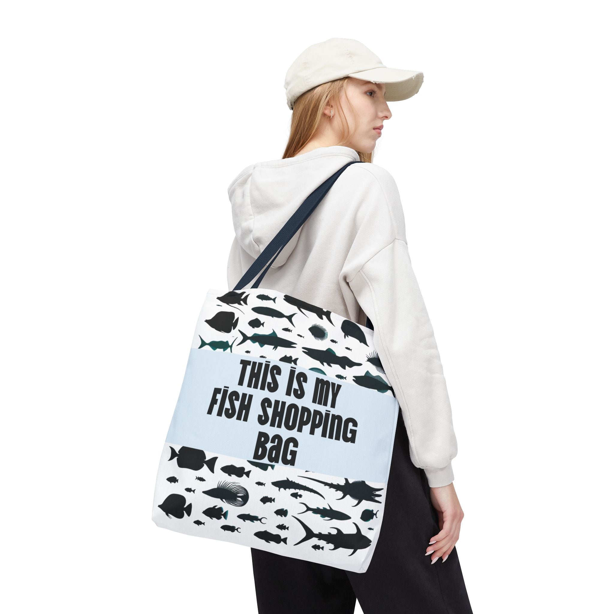 Person holding a tote bag with fish designs and text on a white background