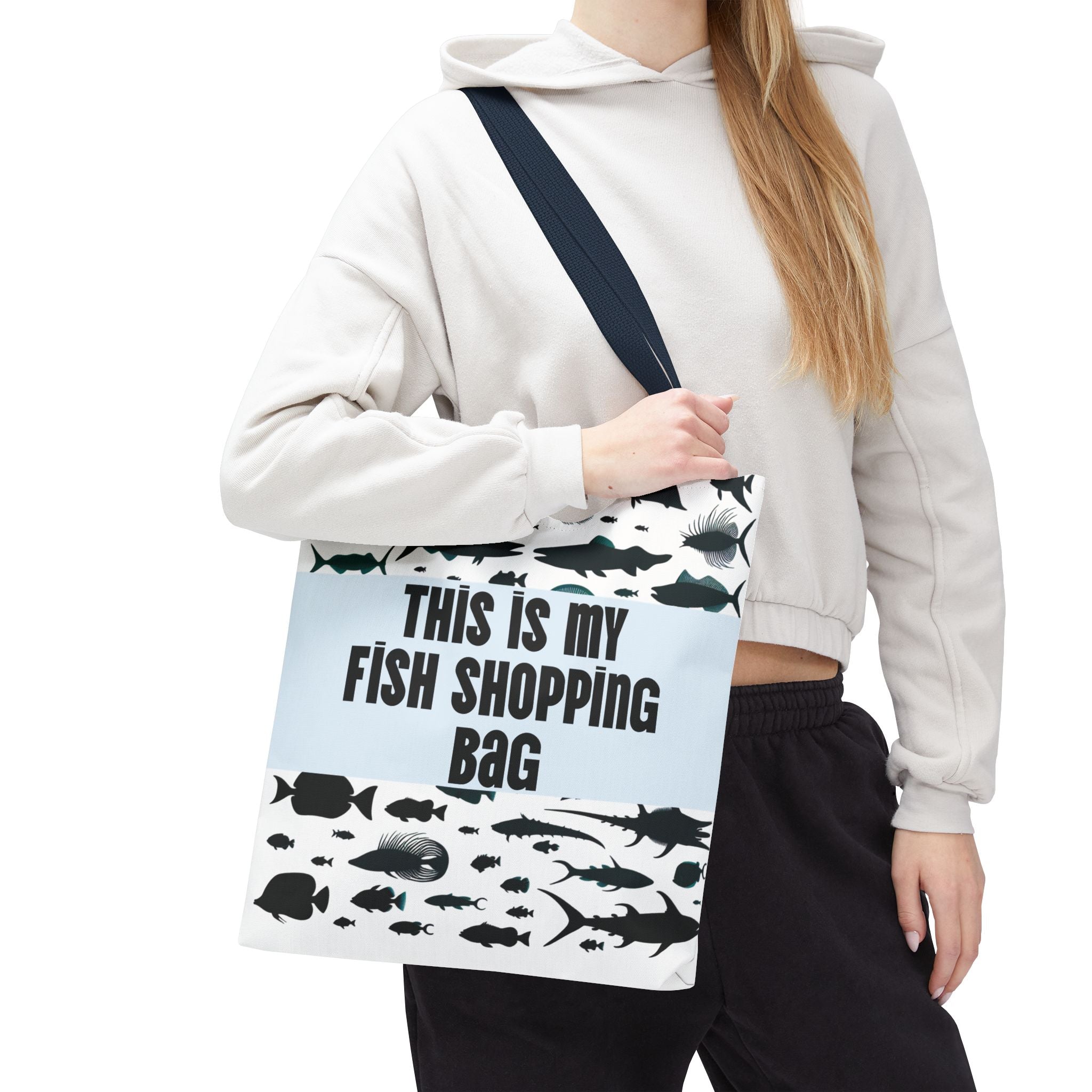 Person holding a tote bag with fish designs and text on a white background