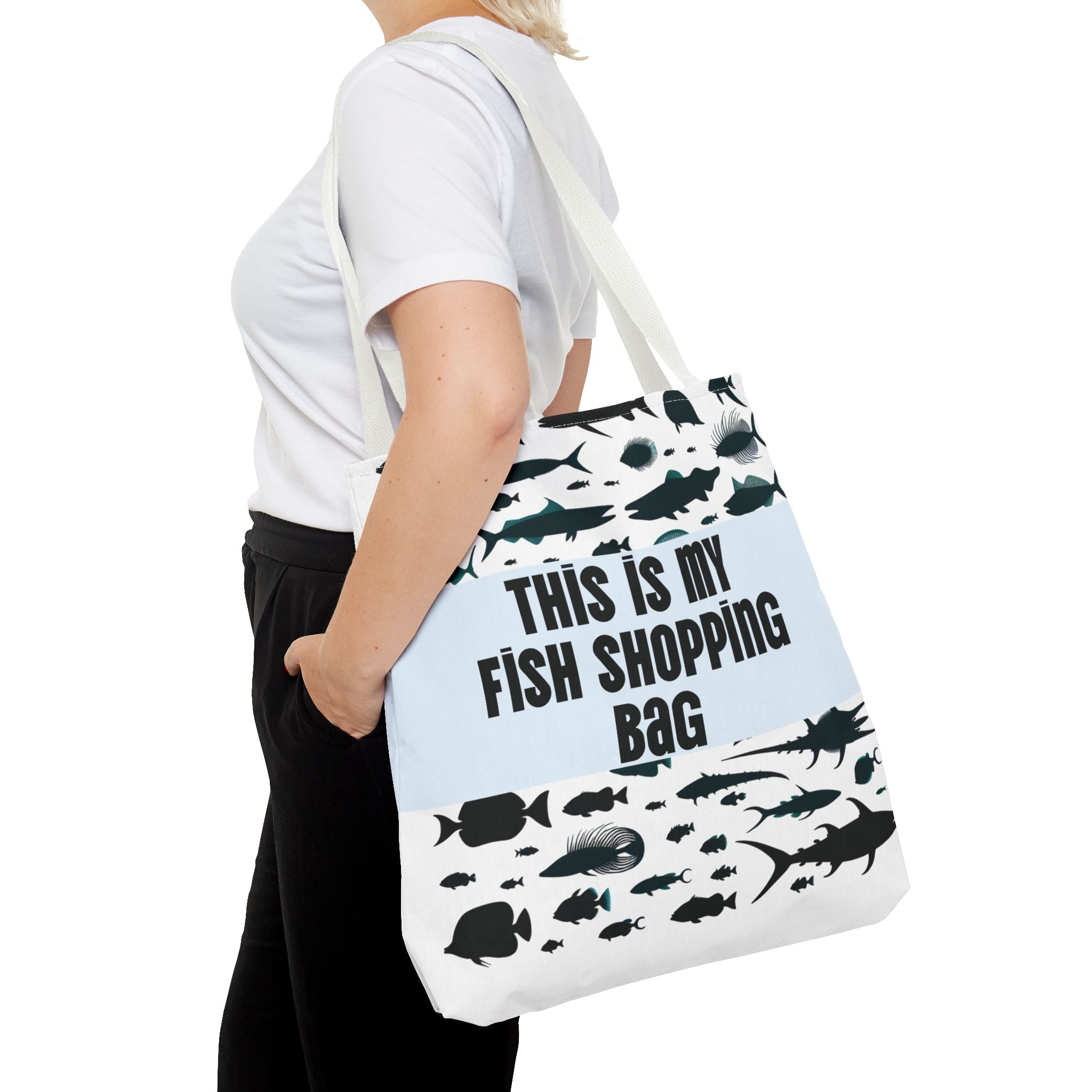 Person holding a tote bag with fish designs and text on a white background
