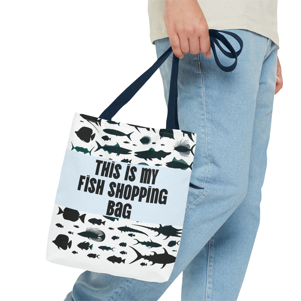 Tote bag with fish design and text held by a person wearing jeans