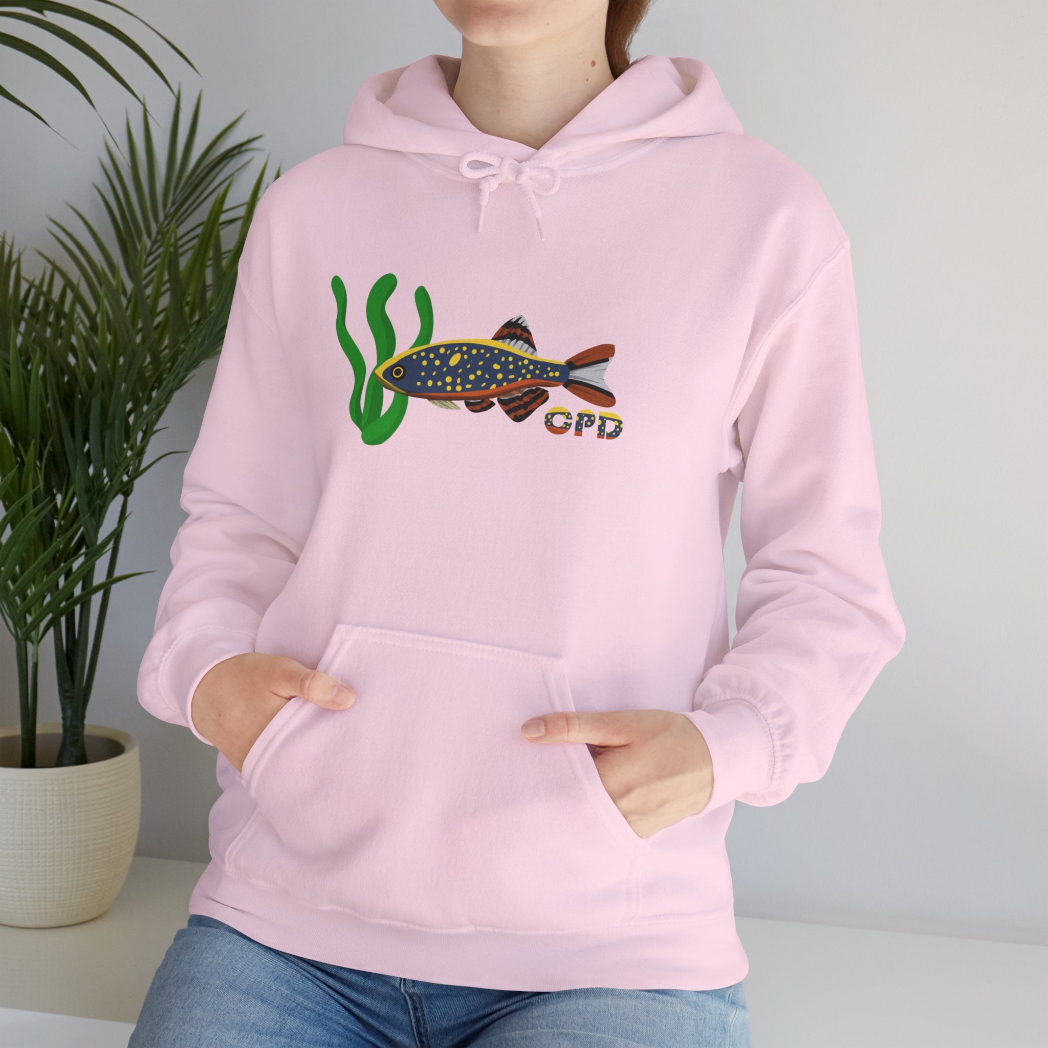 Woman sitting beside plant in pink hoodie with Celestial Pearl Danio graphic