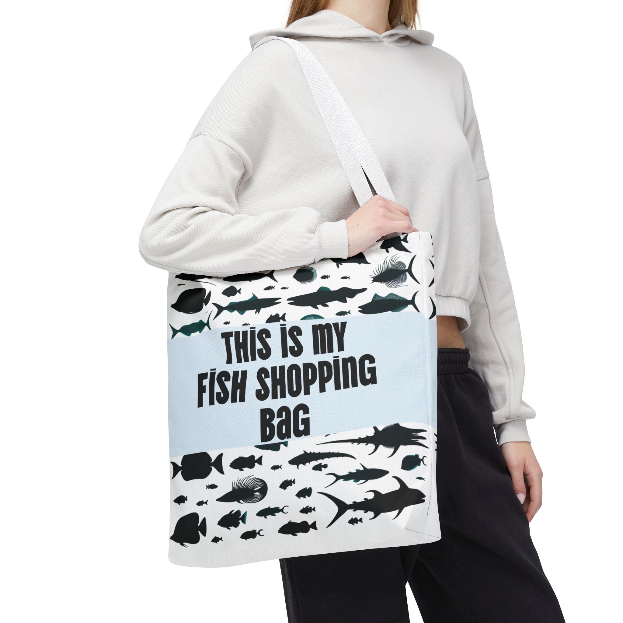 Person holding a tote bag with fish designs and text on a white background