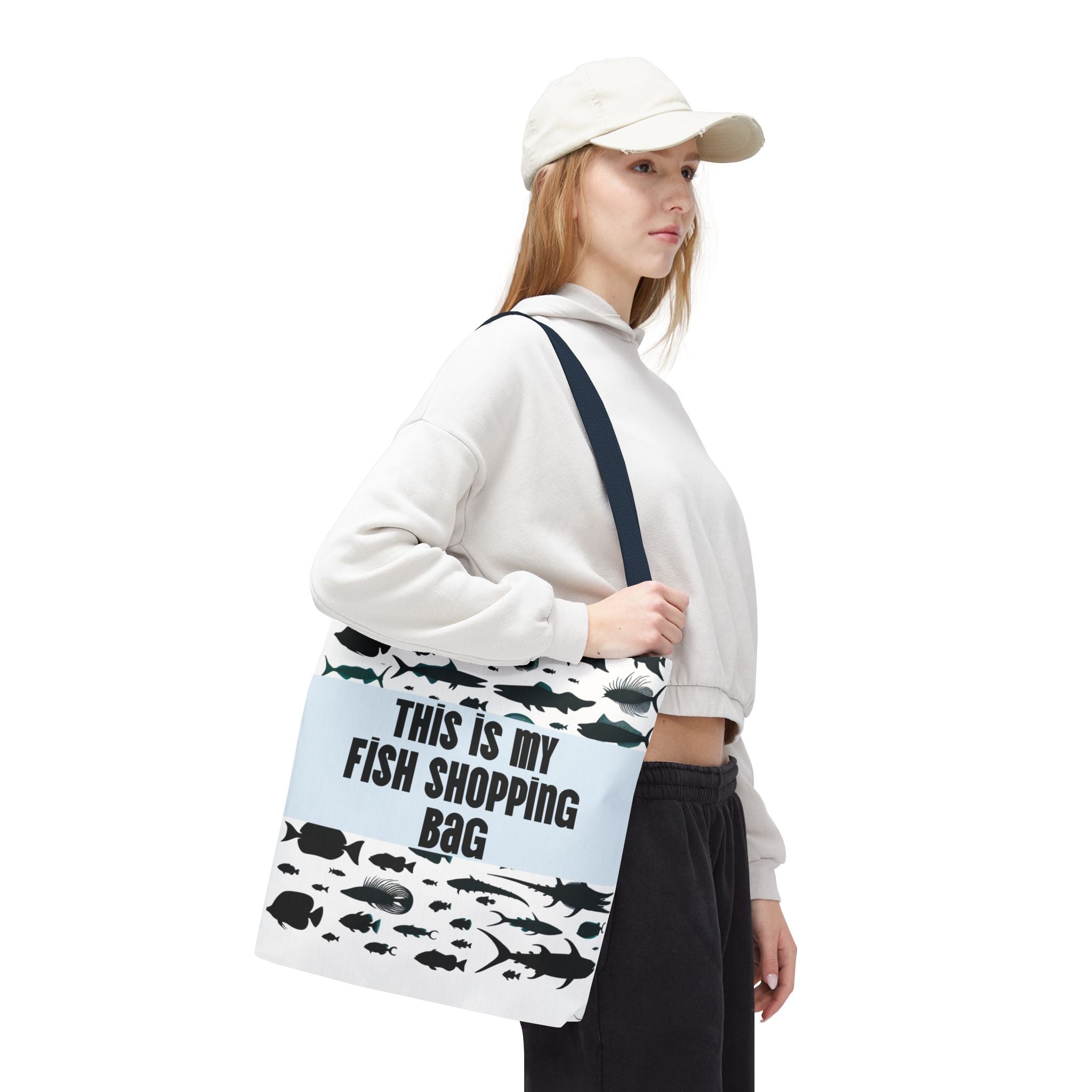 Person holding a tote bag with fish designs and text on a white background