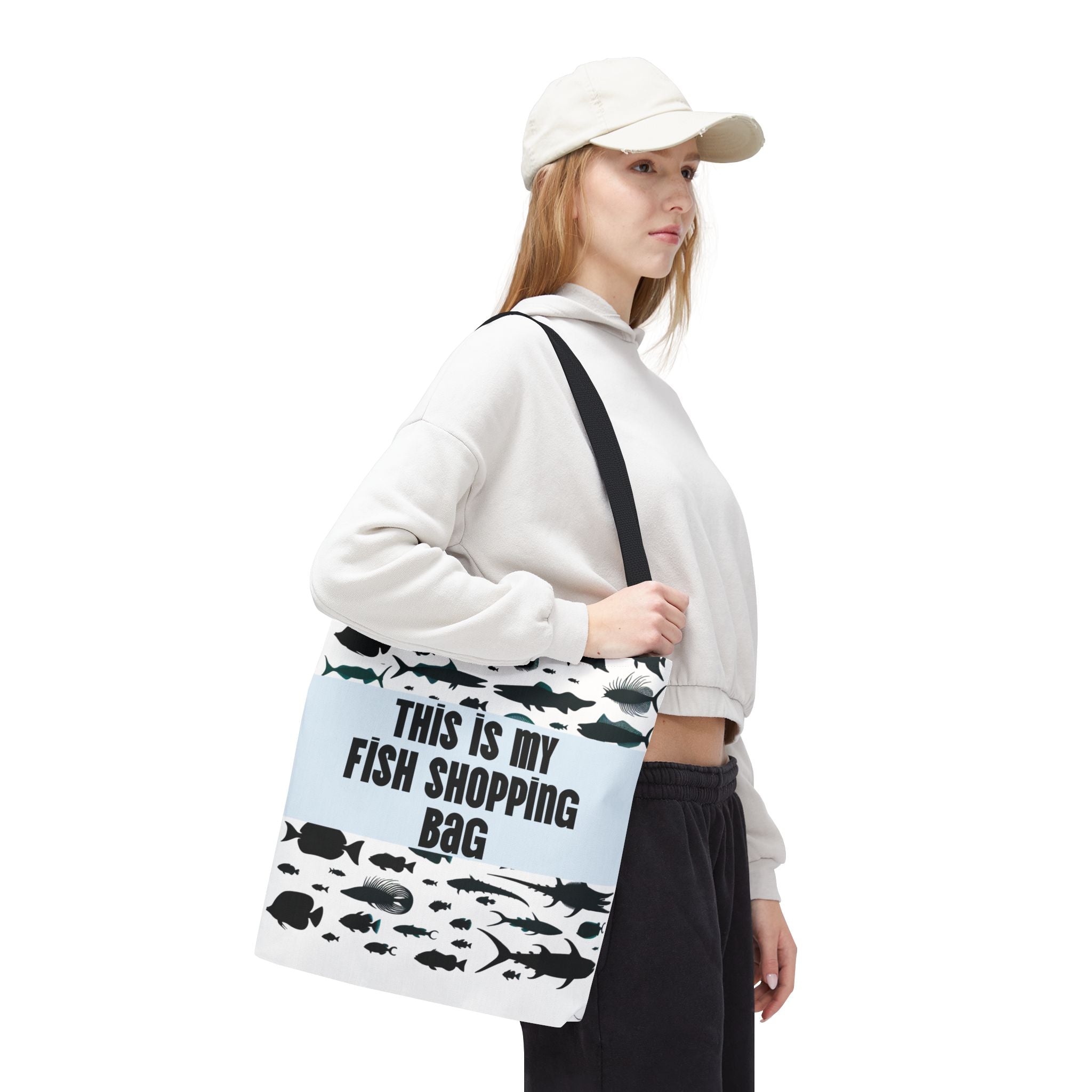 Person holding a tote bag with fish designs and text on a white background